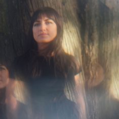 a women with fair skin and dark hair posing in front of a tree