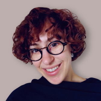 Portret van Nora Goerne. Nora is in de dertig, heeft krullend haar en draagt een bril