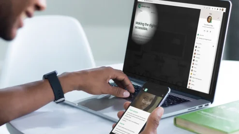 A participant of a digital accessibiility empathy lab, with a persona on his smartphone and a simulation tool on his computer